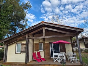 A rustic cabin with a covered porch, wooden exterior, and a red umbrella.
