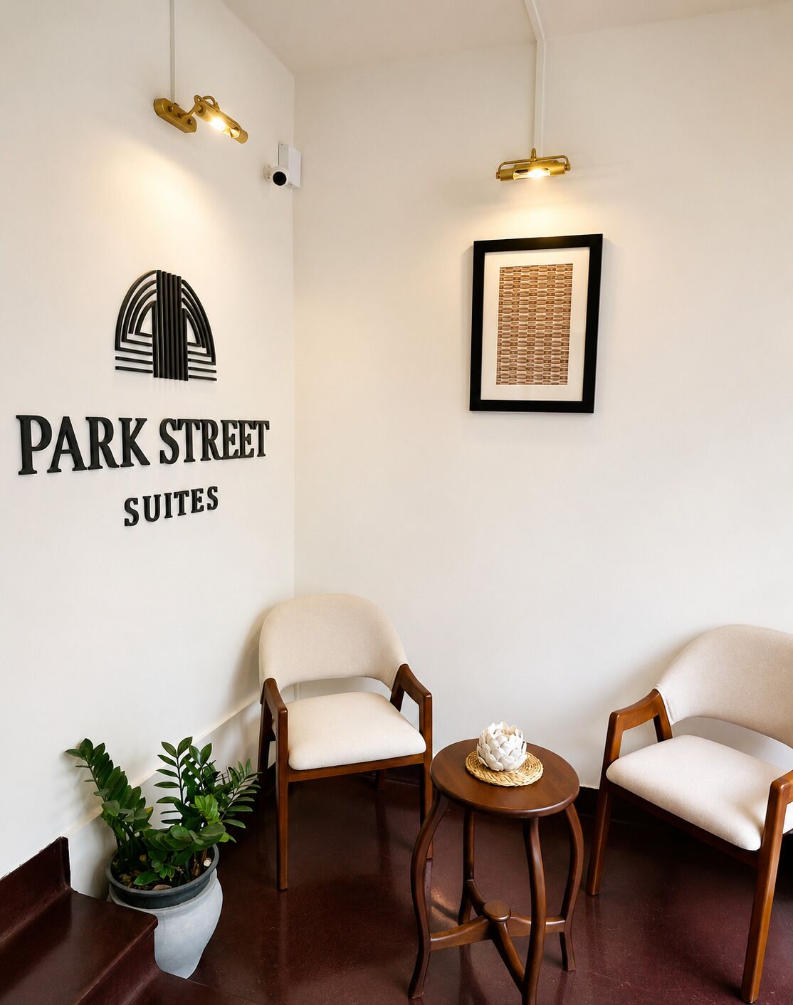 A reception area with a sign for 'Park Street Suites,' two upholstered chairs, a small round table with a decorative item, and a potted plant.