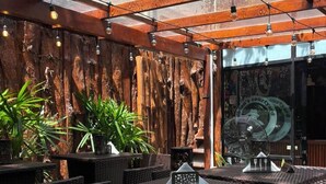 An outdoor seating area with wicker furniture, potted plants, and a wooden pergola structure. - Park Street Suites - Colombo (Colombo)