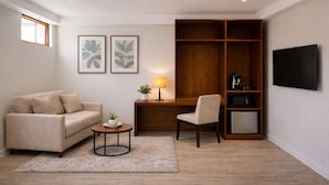 A living room with a sofa, a desk with a chair, a TV, and a wooden bookshelf. - Park Street Suites - Colombo (Colombo)