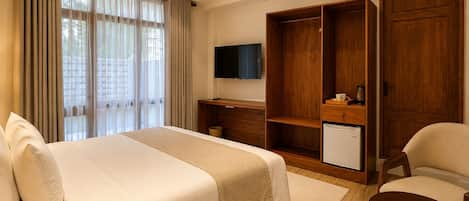A hotel room with a bed, a desk, a TV, a wardrobe, and a small refrigerator.
