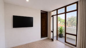 A room with a large window, a flat-screen TV mounted on the wall, and a potted plant. - Park Street Suites - Colombo (Colombo)