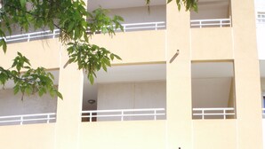 Un edifici de diversos pisos amb entrada a nivell del carrer, un balcó al segon pis i un cartell amb dibuixos de ones blaves.