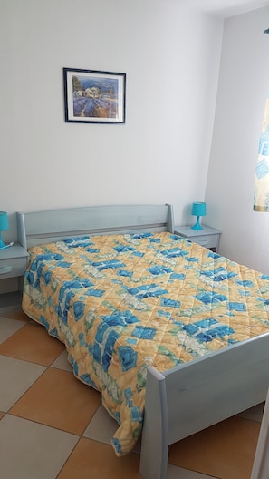 A bedroom with a bed, two bedside tables, a nightstand, a framed picture on the wall, and a window with curtains. - Appart. Air conditioning, beach access, 6 people, terrace, private parking CAP D'AGDE Rochelongue (Cap d'Agde)