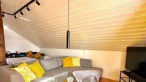 Un soggiorno moderno con un divano modulare grigio, pavimento in legno, un tavolino da caffè in vetro e un mobile TV nero.
