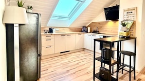 Una cucina moderna con pavimento in legno, un lucernario e una zona pranzo con tavolo e sedie.