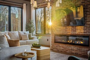 A modern living room with a sofa, a coffee table, and a fireplace. - Indoor Pool Cabin w/ Views, Hot Tub & Game Room (Sevierville)