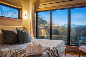 A bedroom with a large window offering a view of the outdoors. - Indoor Pool Cabin w/ Views, Hot Tub & Game Room (Sevierville)
