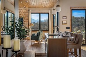 A modern kitchen with a large island, wooden ceiling, and large windows offering a view of the mountains. - Indoor Pool Cabin w/ Views, Hot Tub & Game Room (Sevierville)