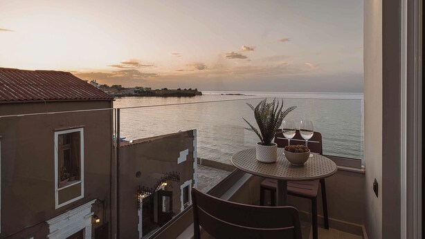 A balcony with a table, chairs, and a potted plant. - Chania Mocenigo Luxury Room I - Seaview,15m to sea (Chania)
