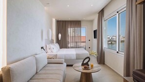 A hotel room with a sofa, a bed, a round wooden table with fruit and juice, and a view of the sea. - Chania Mocenigo Luxury Room I - Seaview,15m to sea (Chania)