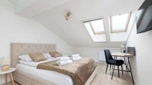 Ein Schlafzimmer mit Bett, Schreibtisch und Stuhl. Über dem Schreibtisch befinden sich Dachfenster.