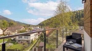 Ein Balkon mit einem Korbstuhl, zwei Tassen und einer Zeitschrift.