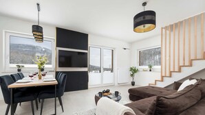 Ein zeitgemäßer Wohnraum mit Essbereich, Sofa und Treppe.