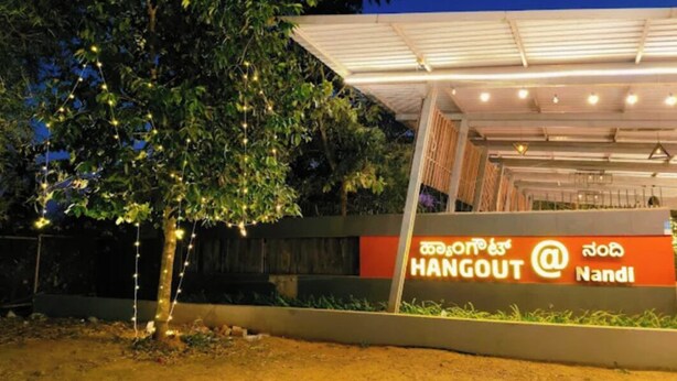 A modern building with a sign that reads "HANGOUT @ Nandi" in English and another language. - Hangout at  Nandi Hills (Devanahalli)