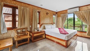 A bedroom with a large bed, wooden nightstands, a wooden bench, and a window with curtains. - Chanta Boutique Place (Ubon Ratchathani)