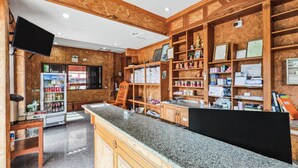 A reception area with a counter, wooden paneling, a refrigerator, and a television. - Chanta Boutique Place (Ubon Ratchathani)