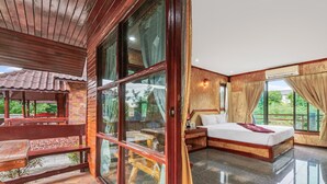 A room with a large bed, a wooden bench, and a view of greenery outside. - Chanta Boutique Place (Ubon Ratchathani)