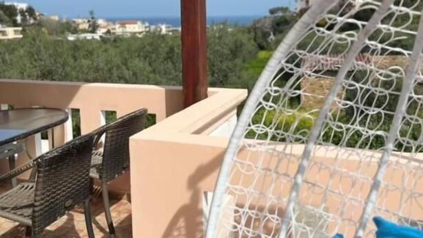 Een balkon met een hangmat, tuinmeubilair en uitzicht op zee.