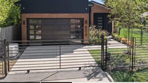 A modern two-story building with a garage, a paved driveway, and a metal fence. - One Story + Generator & Gated Near HTX Medical (Houston)