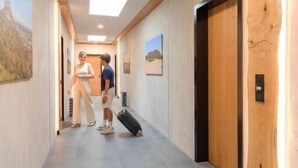 A hallway with wooden walls and a tiled floor, leading to a door with a light switch. - Hohentwiel Apartments (Singen)