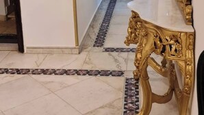 A hallway with a marble floor, a golden table with a lion design, and a framed picture on the wall. - Spacious 3-Bedroom Apartment in Central Cairo with City View (Cairo Governorate)