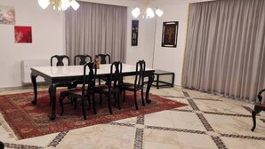 A dining area with a rectangular table, six chairs, a red patterned rug, and a chandelier. - Spacious 3-Bedroom Apartment in Central Cairo with City View (Cairo Governorate)