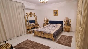 A bedroom with a large bed, ornate gold furniture, and a chandelier. - Spacious 3-Bedroom Apartment in Central Cairo with City View (Cairo Governorate)