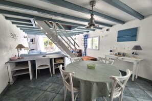 Ein Essbereich mit einem runden Tisch, Stühlen, einer Treppe und einem Deckenventilator.