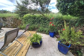 Eine Holzterrasse mit Stühlen, Blumentöpfen und einer Steinmauer.