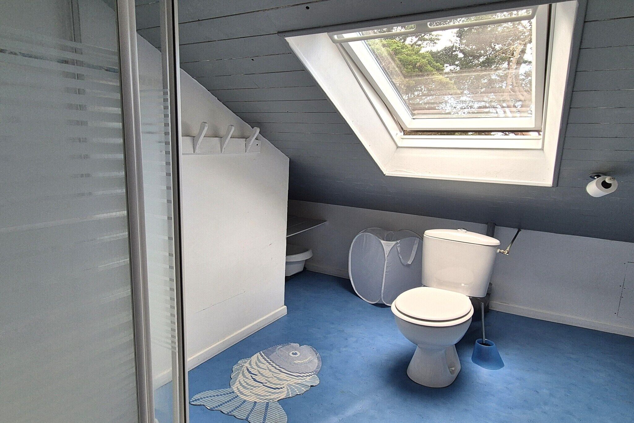 Un baño con tragaluz, inodoro y diseño de piso azul.