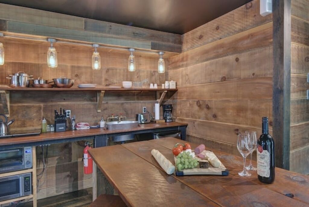 Une cuisine rustique avec des murs en bois, un plan de travail en bois et des luminaires suspendus.