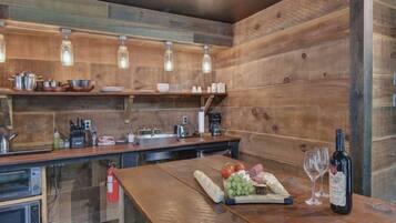 Une cuisine rustique avec des murs en bois, un plan de travail en bois et des luminaires suspendus.