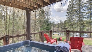 Un bain à remous sur une terrasse en bois, avec vue sur une forêt et un lac.