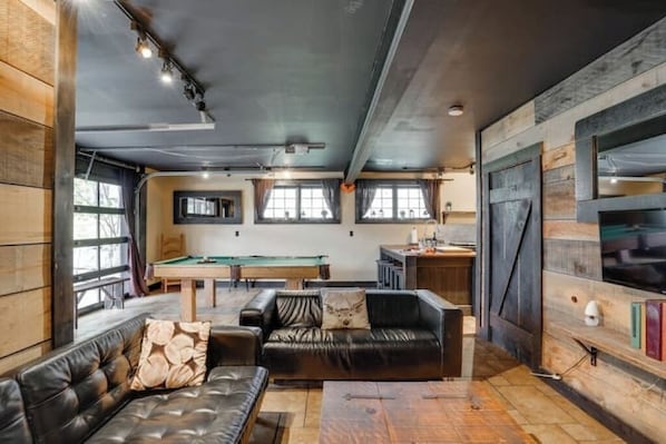 Una habitación acogedora con mesa de billar, sofá de cuero y paredes de madera.