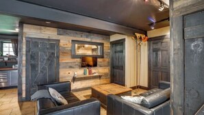 Un salon moderne avec une cheminée, des canapés en cuir et un mur d’accent en bois.