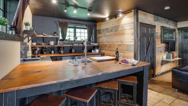 Une cuisine moderne dotée d’un grand îlot central, de touches de bois et d’un plafond foncé.