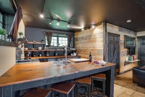 Una cocina moderna con una isla grande, detalles de madera y techo oscuro.