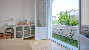 Una stanza con un'ampia porta-finestra scorrevole che dà su un balcone con vista su una zona residenziale.