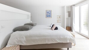 Camera da letto moderna con un letto grande, una testiera, un comodino, una mensola a parete e un'ampia finestra con vista.