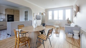 Una cucina moderna con mobili in legno, una zona pranzo con tavolo e sedie rotonde e un soggiorno con divano e tavolino.