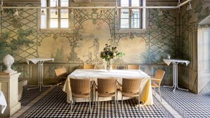 Un comedor con suelo a cuadros, una mesa dispuesta para cuatro personas y un mural en la pared.