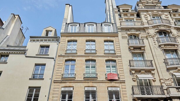 Ein mehrstöckiges Gebäude mit klassischer Architektur, das mit verzierten Balkonen und großen Fenstern gestaltet ist.