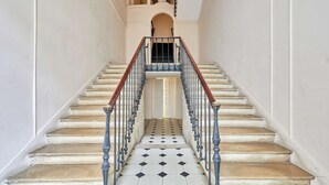 Eine imposante Treppe mit schwarz-weiß gefliestem Boden führt zu einer Tür oben.