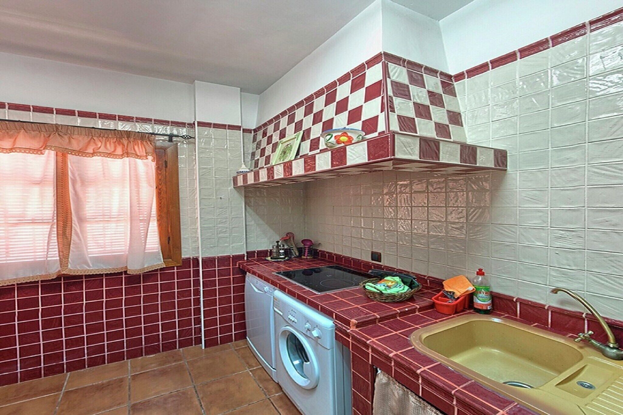 A compact kitchen with a washing machine, a sink, and a tiled backsplash.