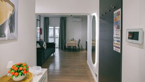 A modern living room with a dining area, a sofa, a table set for two, and a wall-mounted air conditioner.