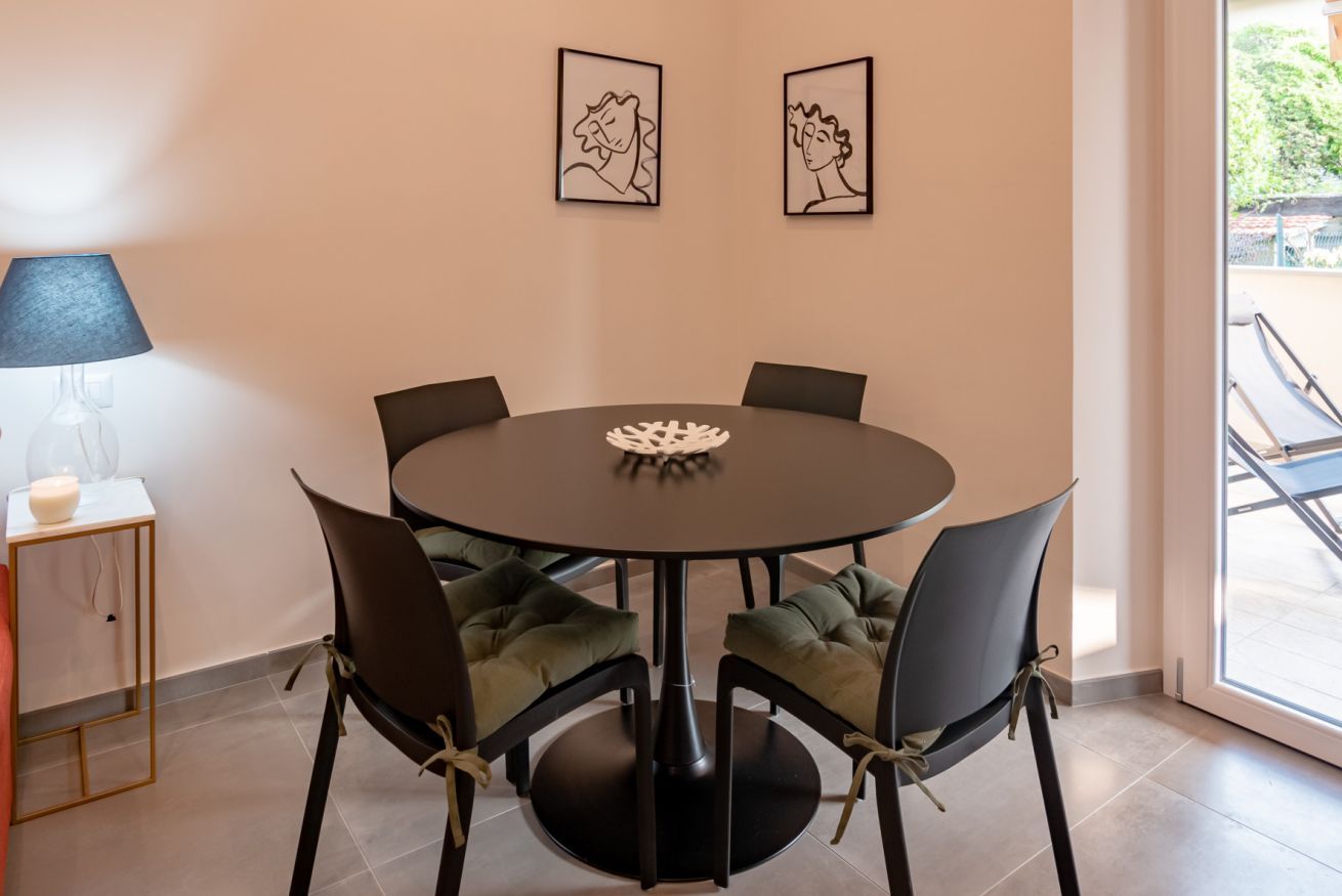Un tavolo rotondo da pranzo con sei sedie, una lampada e due quadri appesi al muro.