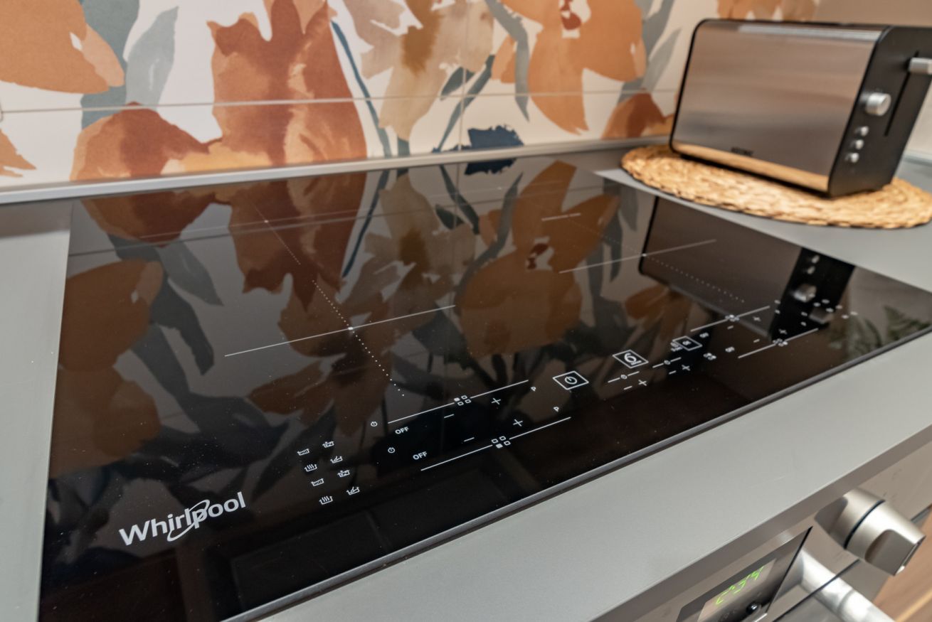 Una cocina moderna con lavavajillas Whirlpool integrado y una campana extractora de acero inoxidable elegante.
