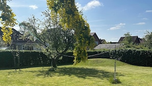 A well-maintained grassy yard with a tree, a metal pole, and a hedge. - Basement Apartment in Villa (Odense)