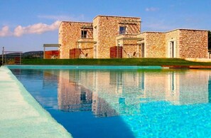 A stone building with a swimming pool in front. - Stone Bay Houses Kalamaki Messinia (Messini)